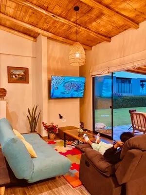 two people sitting in a living room playing a video game at Casa de Campo Bamboo con Piscina temperada in Lima