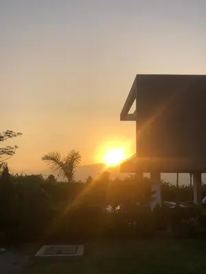 a sunset behind a house with the sun setting at Casa de Campo Bamboo con Piscina temperada in Lima