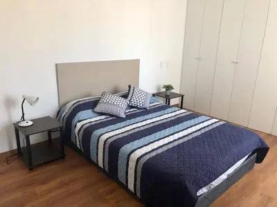 a bedroom with a bed with two tables and a lamp at Hermoso y amplio departamento en zona tranquila en Jesús Maria in Lima