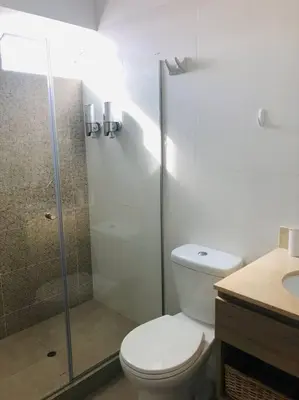 a bathroom with a toilet and a glass shower at Hermoso y amplio departamento en zona tranquila en Jesús Maria in Lima