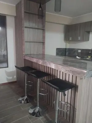 a kitchen with two bar stools and a counter at Departamento Céntrico y Acogedor in Huancayo