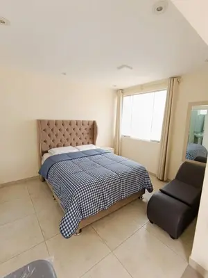 a bedroom with a bed and a chair and a window at Hermoso Penthouse con jacuzzi en terraza in Lima