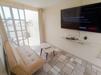 a living room with a chair and a flat screen tv at Hermoso Penthouse con jacuzzi en terraza in Lima