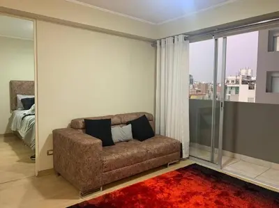 a living room with a couch and a large window at Vive Cerca a Miraflores Apart. in Lima