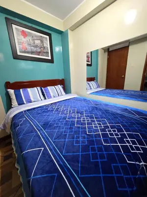 two beds in a room with blue walls at Hospedaje Escorpio in Lima