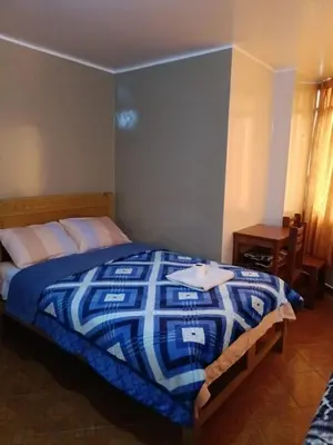 a bedroom with a bed with a blue and white comforter at Hospedaje Escorpio in Lima