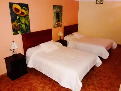 a bedroom with two beds and a painting on the wall at Hotel Sevilla in Ayacucho
