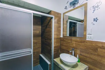 a bathroom with a glass shower and a sink at PAKARINA HOUSE in Cusco