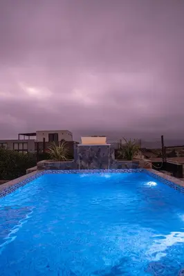 a large blue swimming pool with a cloudy sky at Mar y campo Casa Huarca in La Isla