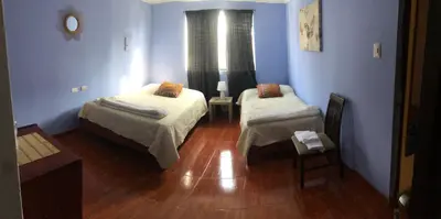 a room with two beds in a room with blue walls at Pedraza house Airport in Lima