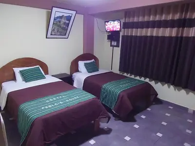 a hotel room with two beds and a television at Hostal Pablo's House in Machu Picchu