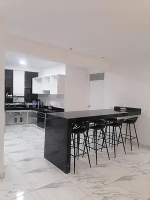 a kitchen with a black and white counter and stools at Alquilo Casa playa in San Antonio