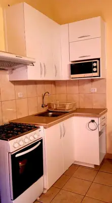 a kitchen with white cabinets and a stove and a sink at Kanata Properties 2 in Lima
