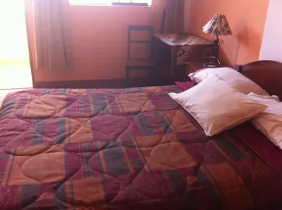 a bedroom with a bed with a quilt on it at Hostal Tres Máscaras in Ayacucho