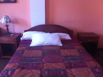 a bedroom with a bed with a red wall at Hostal Tres Máscaras in Ayacucho
