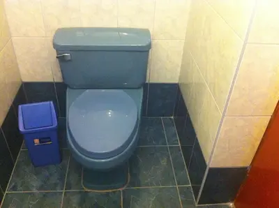 a bathroom with a blue toilet and a trash can at Hostal Tres Máscaras in Ayacucho