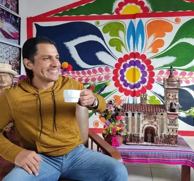 a man sitting on a chair holding a cup of coffee at Hotel San Francisco de Paula Ayacucho in Ayacucho