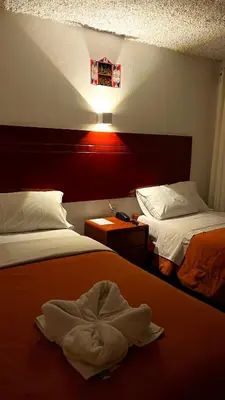 a hotel room with two beds and a towel laying on the bed at Hotel San Francisco de Paula Ayacucho in Ayacucho