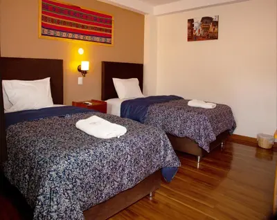 a hotel room with two beds with towels on them at El Chasqui in Ollantaytambo