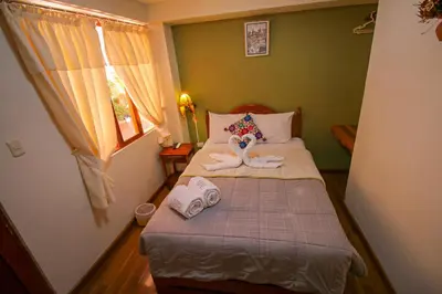 a small bedroom with a bed with towels on it at El Chasqui in Ollantaytambo