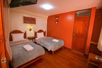 two beds in a room with orange walls at El Chasqui in Ollantaytambo