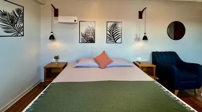 a bedroom with a bed and a blue chair at Casa Encuentro San Blas in Cusco