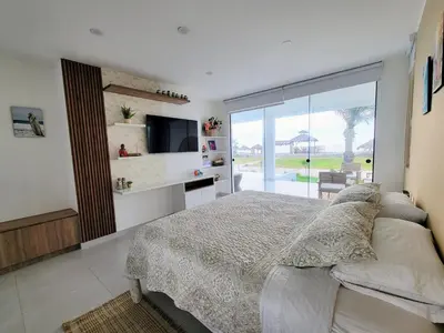 a bedroom with a bed and a sliding glass door at HERMOSA CASA CON PISCINA FRENTE AL MAR - PRIMERA FILA in Chincha Baja
