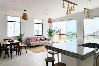 a kitchen and living room with a couch and a table at HERMOSA CASA CON PISCINA FRENTE AL MAR - PRIMERA FILA in Chincha Baja