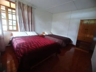 a bedroom with a bed and a dresser and a window at Hospedaje Pinky Lodge in Oxapampa