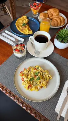 a table with plates of food and a cup of coffee at Casa Tiyay Cusco in Cusco