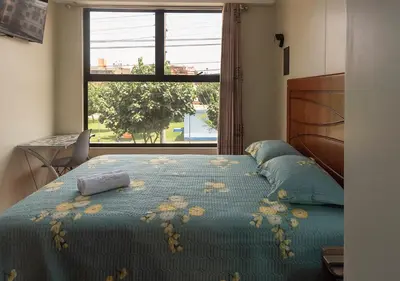 a bedroom with a bed with a blue comforter and a window at Hotel Precursores in Lima