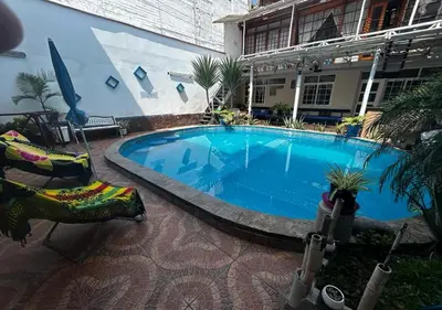 a large swimming pool in a building with two chairs at Playa Arica Backpackers in Arica