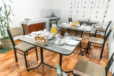 a table with food on it with chairs and orange juice at Escobedo’s Inn Machupicchu in Machu Picchu