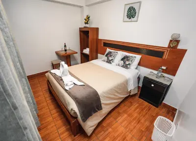 a bedroom with a bed with a white dog on it at Escobedo’s Inn Machupicchu in Machu Picchu