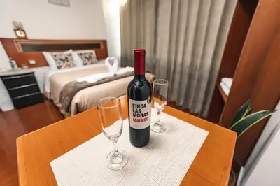 a bottle of wine sitting on a table with two wine glasses at Escobedo’s Inn Machupicchu in Machu Picchu
