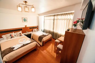 a hotel room with two beds and a television at Escobedo’s Inn Machupicchu in Machu Picchu