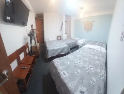 a room with three beds and a flat screen tv at Hospedaje Hamuy's Lodge in Ica