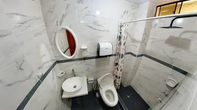 a white bathroom with a toilet and a sink at El Boulevard de Huacachina in Ica