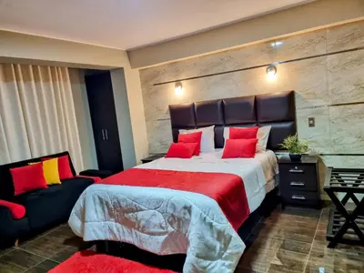 a bedroom with a large bed with red pillows at Hotel del Valle in Huancayo