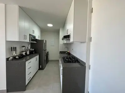 a kitchen with white cabinets and black counter tops at Apartamento de estreno San Bartolo vista Piscina Playa in San Bartolo