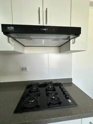 a stove top in a kitchen with white cabinets at Apartamento de estreno San Bartolo vista Piscina Playa in San Bartolo