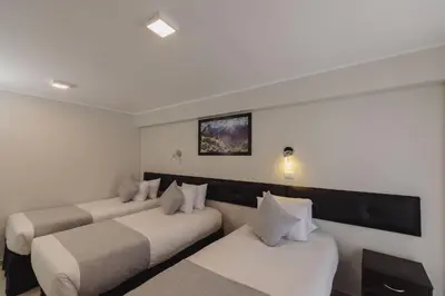 a hotel room with three beds and a tv at Classic Hotel Cusco in Cusco