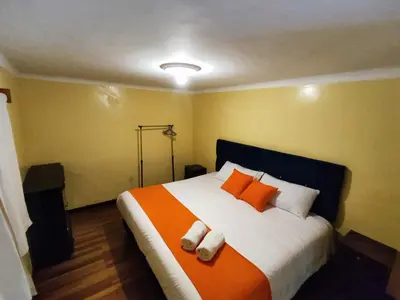 a bedroom with a large bed with orange and white pillows at Qosqo Apartments 3 in Cusco