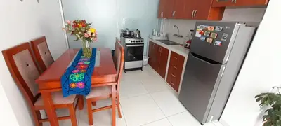 a small kitchen with a table and a refrigerator at Encanta Perú Apartment in Cusco