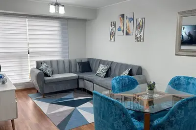 a living room with a gray couch and blue chairs at Departamento de Estreno - cerca a la Playa in Lima