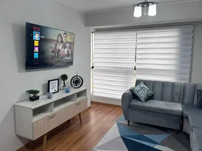 a living room with a couch and a flat screen tv at Departamento de Estreno - cerca a la Playa in Lima