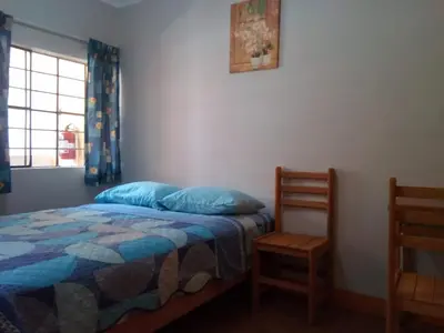 a bedroom with a bed with blue pillows and a window at Brabant Hostal in Nazca