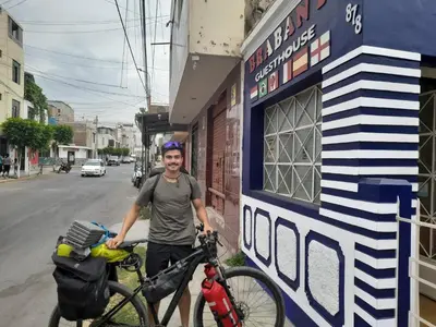 a man standing next to a bike next to a building at Brabant Hostal in Nazca