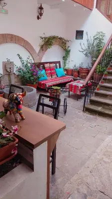 a room with two beds and a table and stairs at Cusco Lodge Hotel Boutique in Cusco