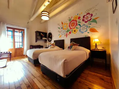 a bedroom with two beds and a painting on the wall at Cusco Lodge Hotel Boutique in Cusco